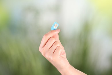 Photo of Woman holding SIM card on blurred background, closeup