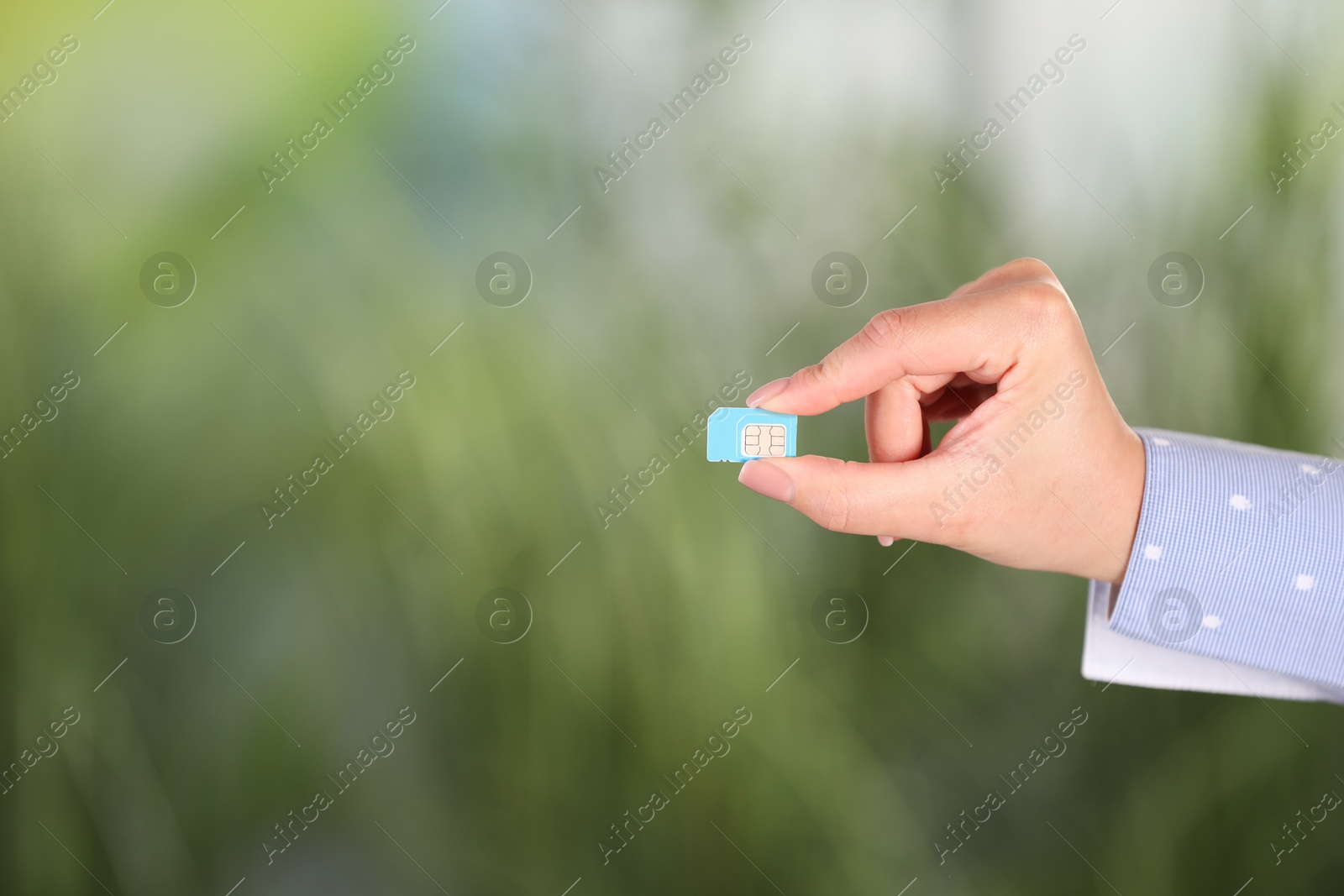 Photo of Woman holding SIM card on blurred background, closeup. Space for text