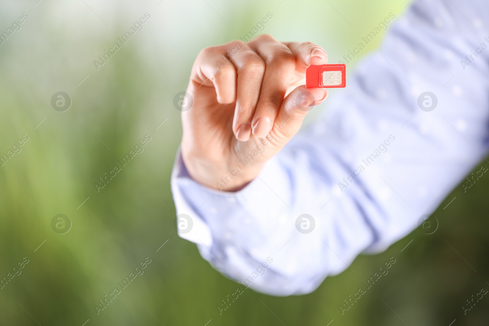 Photo of Woman holding SIM card on blurred background, closeup