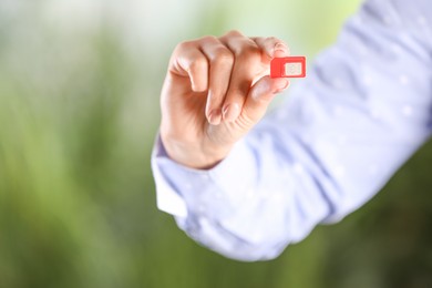 Photo of Woman holding SIM card on blurred background, closeup