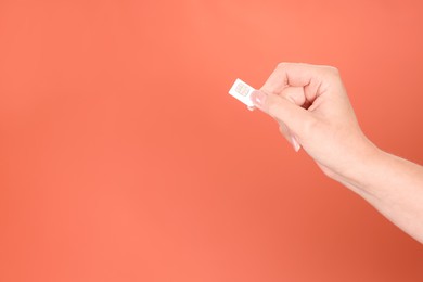 Photo of Woman holding SIM card on terracotta background, closeup. Space for text