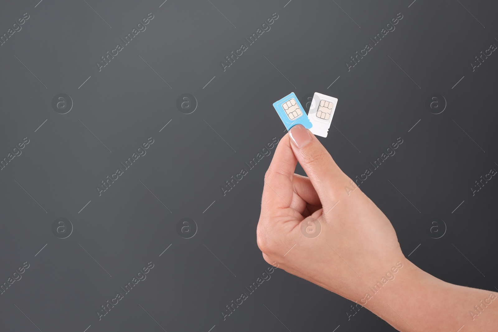 Photo of Woman holding SIM cards on dark grey background, closeup. Space for text