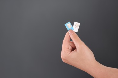 Photo of Woman holding SIM cards on dark grey background, closeup. Space for text