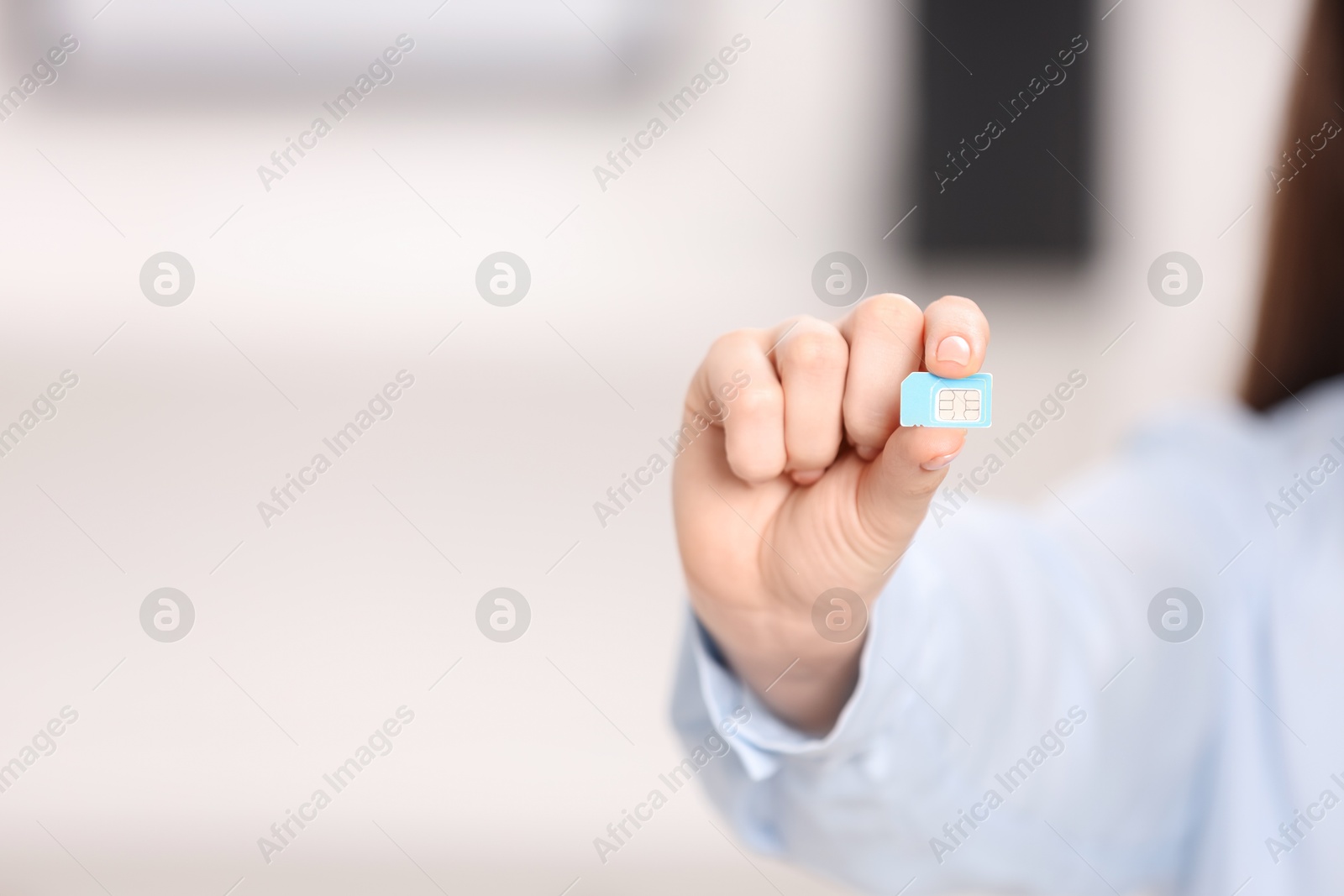 Photo of Woman holding SIM card indoors, closeup. Space for text