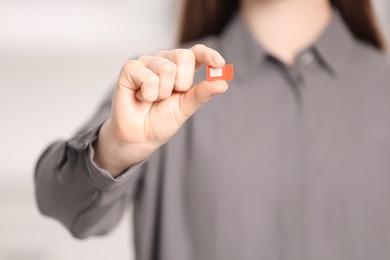 Photo of Woman holding modern SIM card indoors, closeup