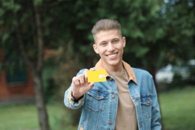 Photo of Happy man with SIM card outdoors, selective focus