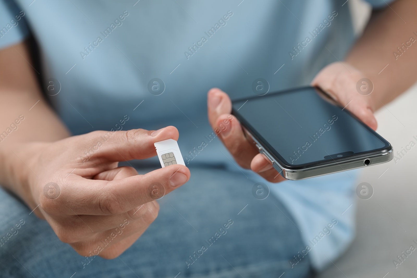 Photo of Man with SIM card and smartphone indoors, closeup