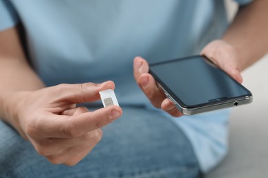 Man with SIM card and smartphone indoors, closeup