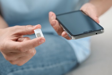 Man with SIM card and smartphone indoors, closeup