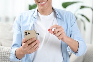 Man with SIM card and smartphone indoors, closeup