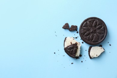 Photo of Whole and broken sandwich cookies on light blue background, top view. Space for text