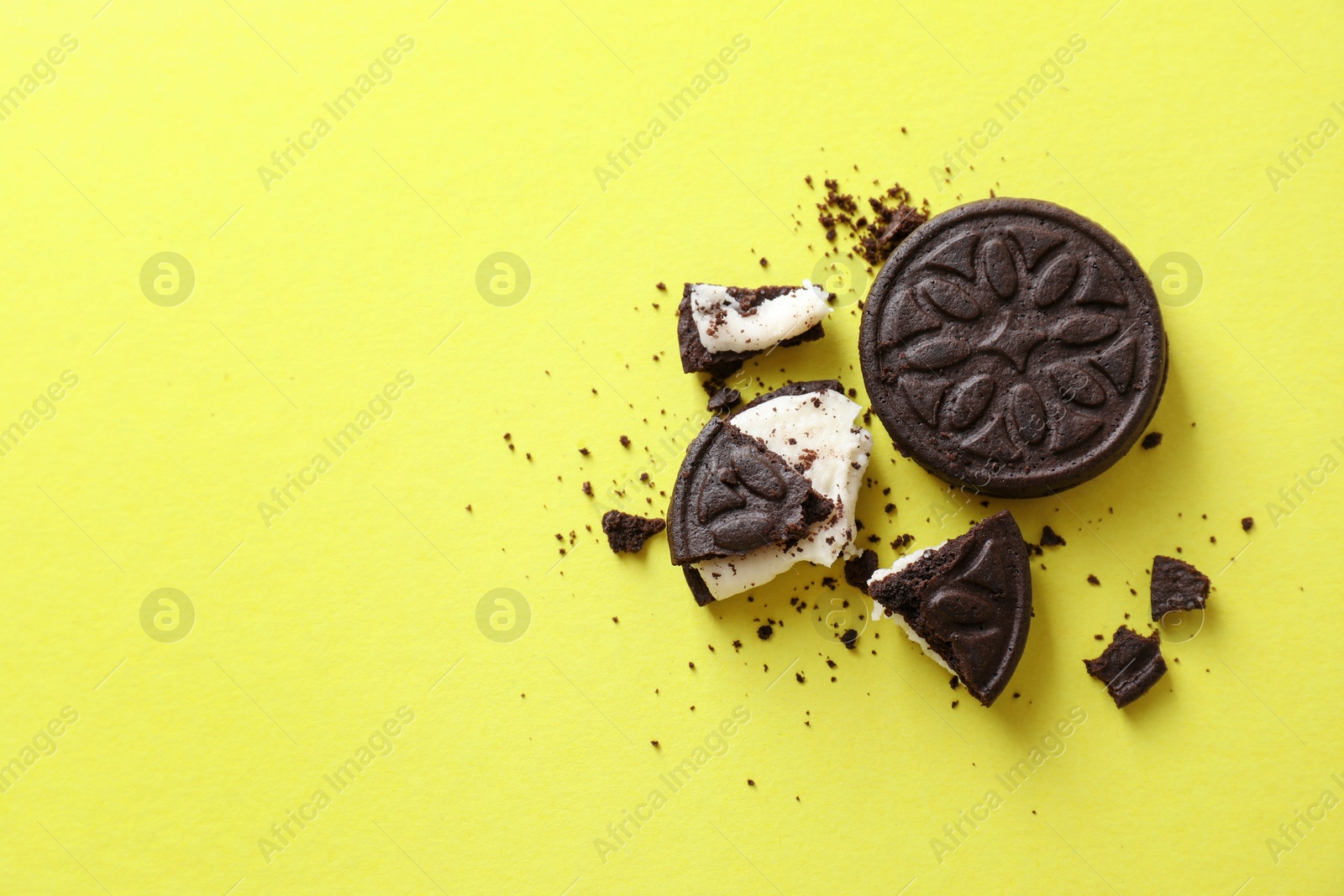 Photo of Whole and broken sandwich cookies on green background, top view. Space for text