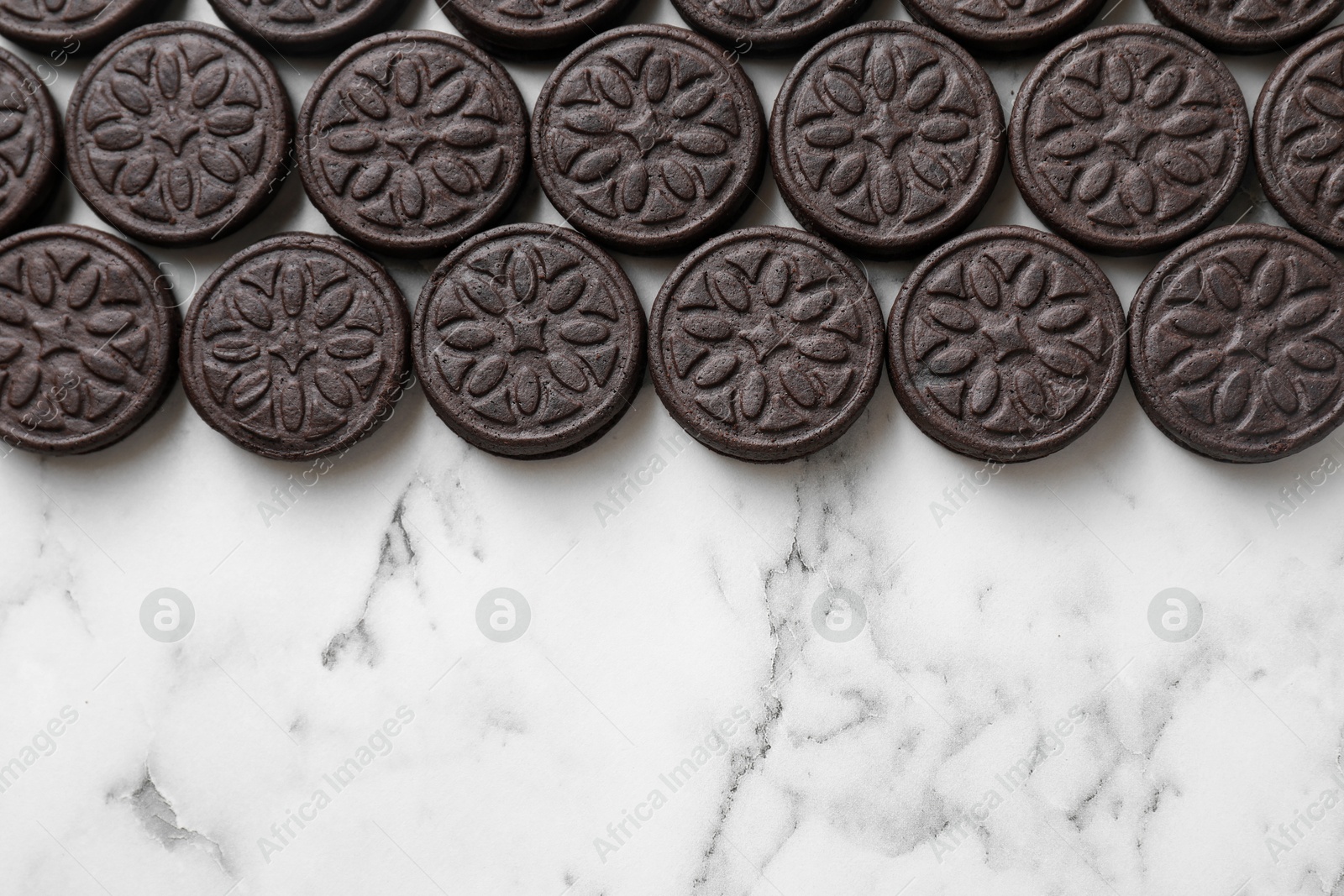 Photo of Tasty sandwich cookies on white marble table, top view. Space for text