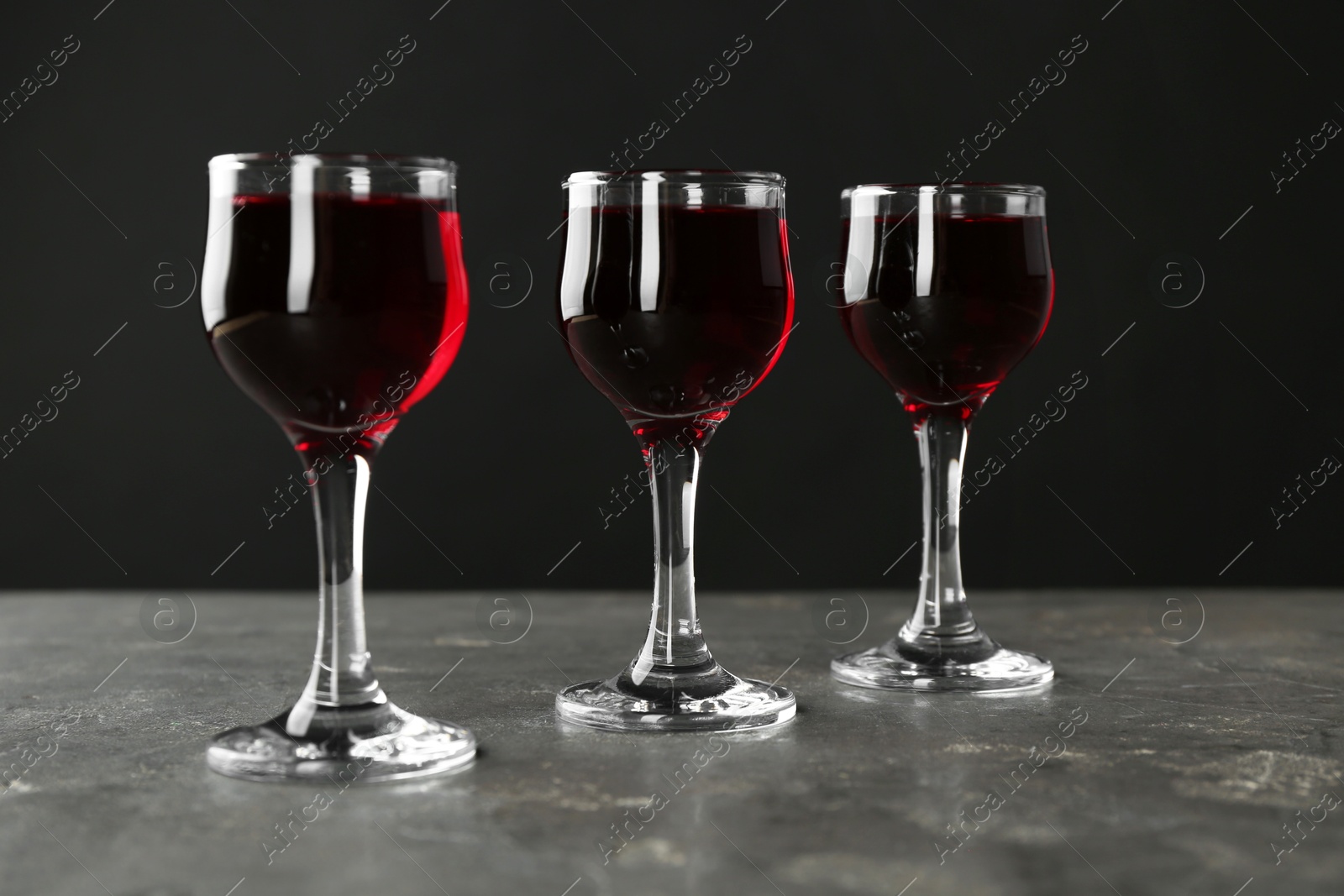 Photo of Delicious cherry liqueur in glasses on grey background