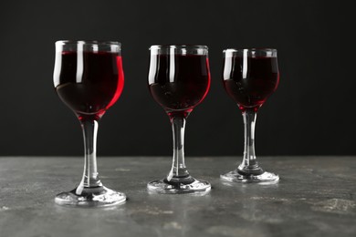 Photo of Delicious cherry liqueur in glasses on grey background