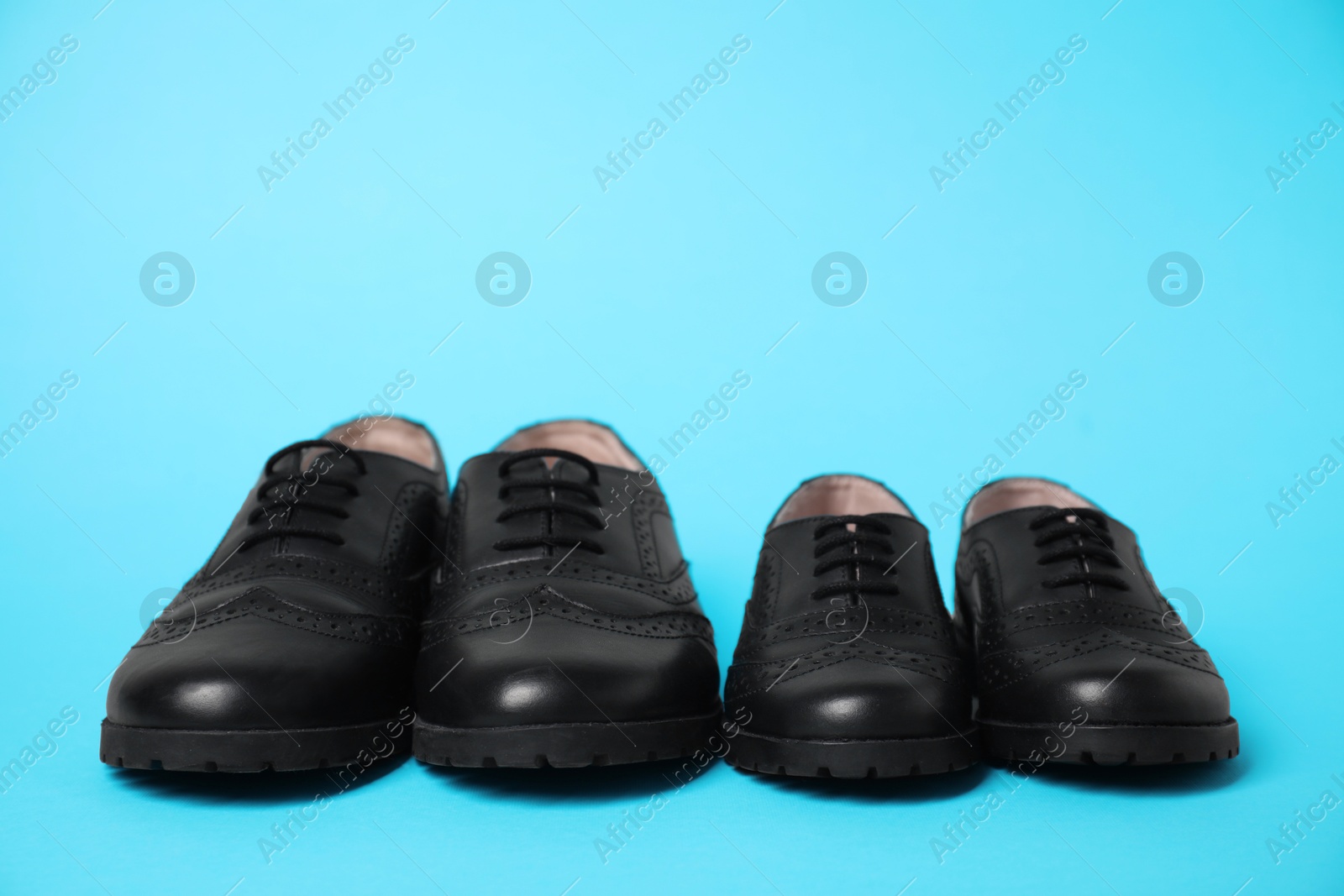 Photo of Big and small shoes on light blue background