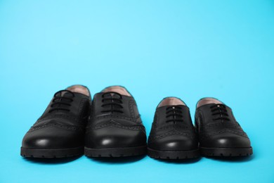 Photo of Big and small shoes on light blue background