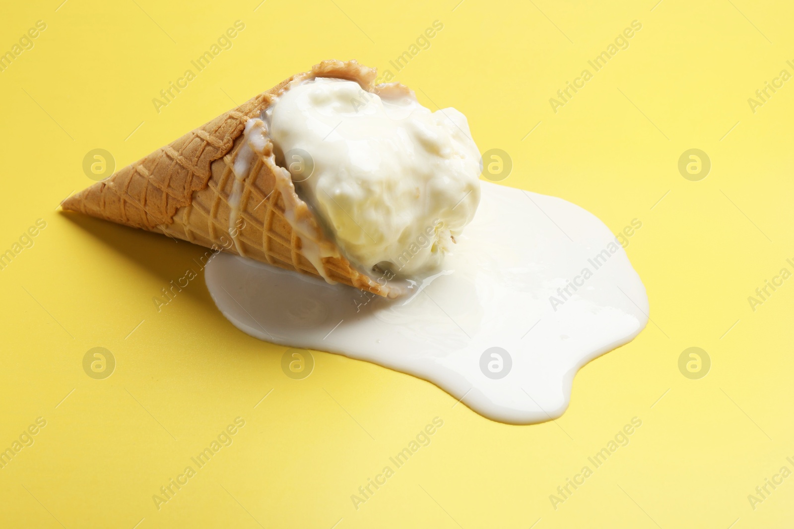 Photo of Melted ice cream in wafer cone on yellow background