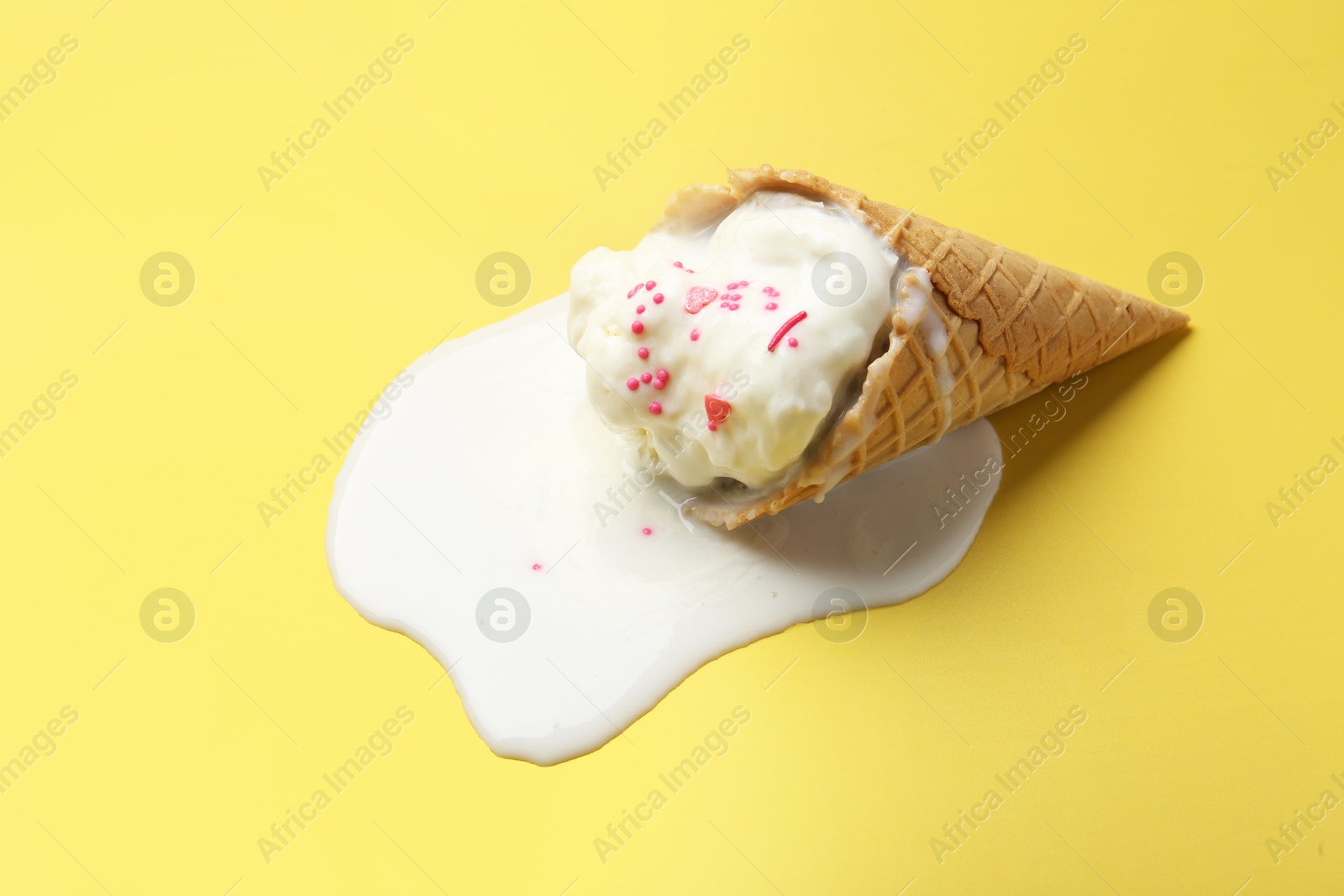 Photo of Melted ice cream in wafer cone on yellow background