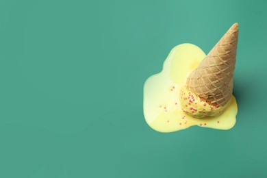 Melted ice cream in wafer cone on pale green background. Space for text