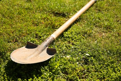 Photo of One rusty shovel on green grass, closeup. Gardening season