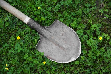 Photo of One rusty shovel on green grass, top view. Gardening season