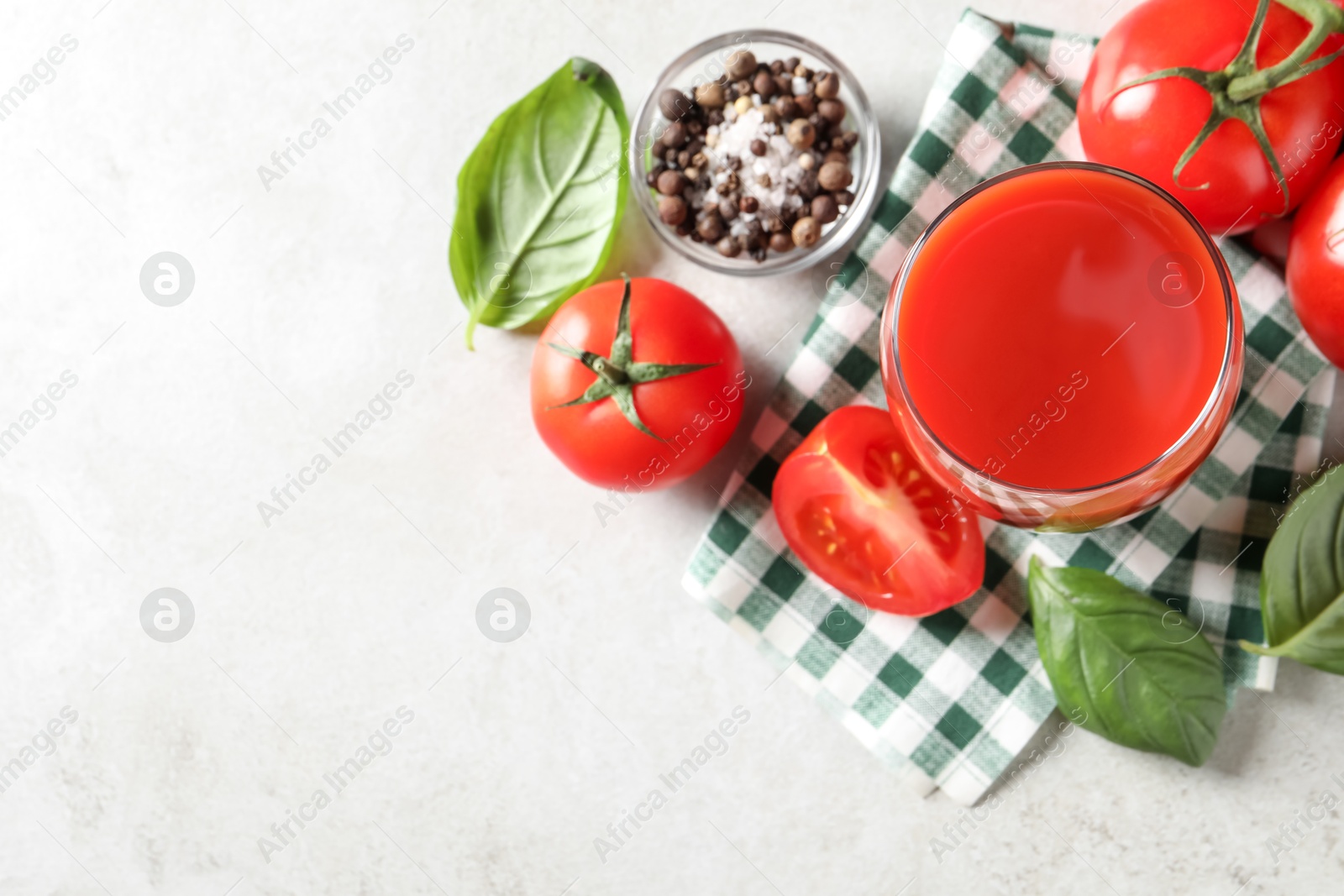 Photo of Tasty tomato juice in glass, spices and fresh vegetables on light table, flat lay. Space for text