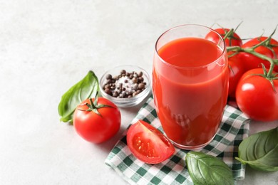 Tasty tomato juice in glass, spices and fresh vegetables on light table, space for text