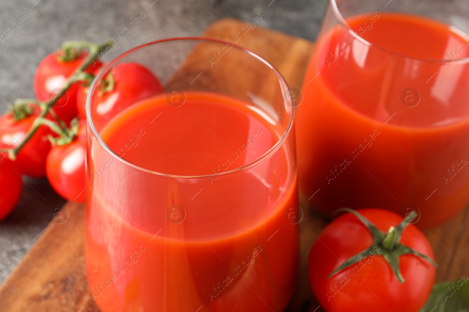 Photo of Tasty tomato juice in glasses and fresh vegetables on table, closeup