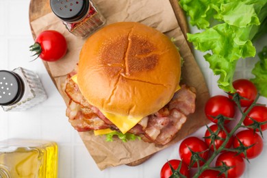 Delicious burger with bacon served on white table, top view