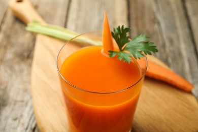 Healthy juice in glass and fresh carrot on wooden table, closeup