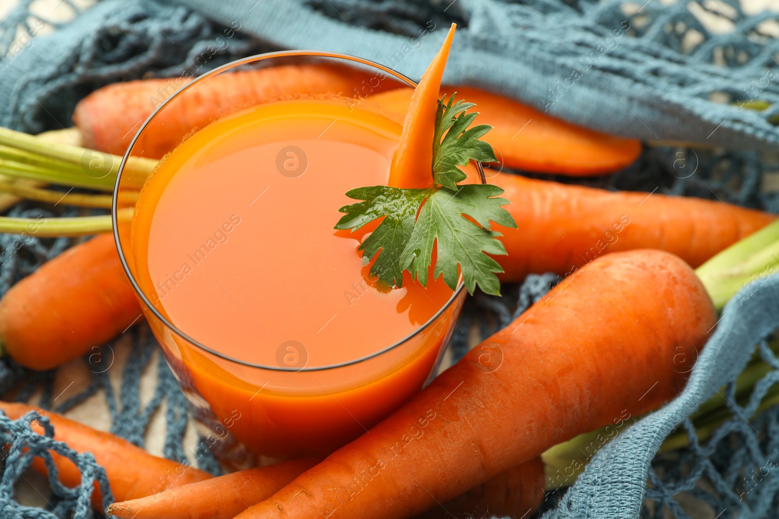 Photo of Healthy juice in glass and fresh carrot on table, closeup