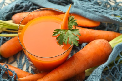 Photo of Healthy juice in glass and fresh carrot on table, closeup