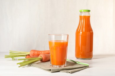 Healthy juice and fresh carrot on white wooden table