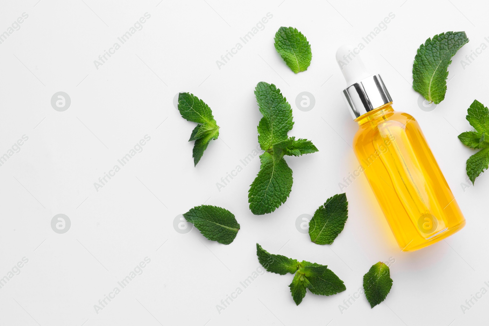 Photo of Bottle of essential oil and mint isolated on white, top view