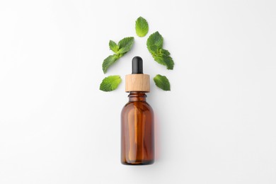 Photo of Bottle of essential oil and mint isolated on white, top view