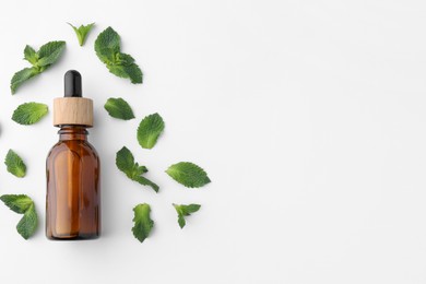 Photo of Bottle of essential oil and mint isolated on white, top view