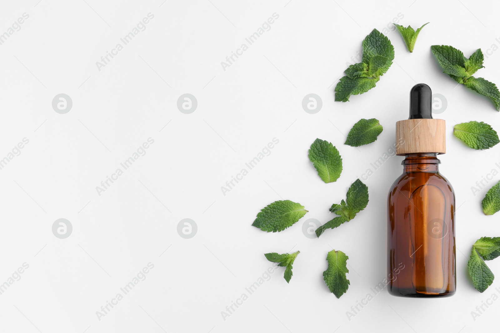 Photo of Bottle of essential oil and mint isolated on white, top view