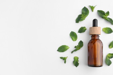 Photo of Bottle of essential oil and mint isolated on white, top view