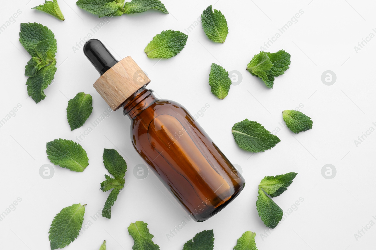 Photo of Bottle of essential oil and mint isolated on white, top view