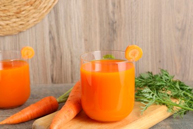 Healthy carrot juice in glasses and fresh vegetables on wooden table