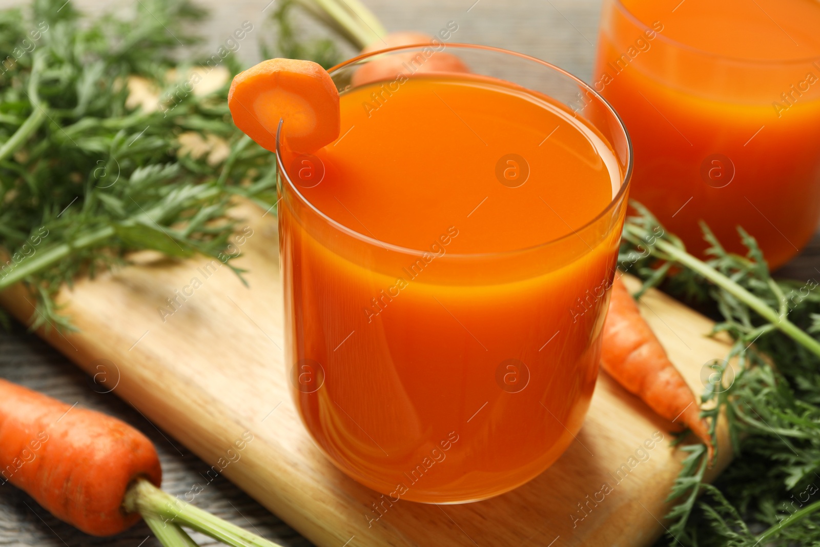 Photo of Healthy carrot juice in glasses and fresh vegetables on table, closeup