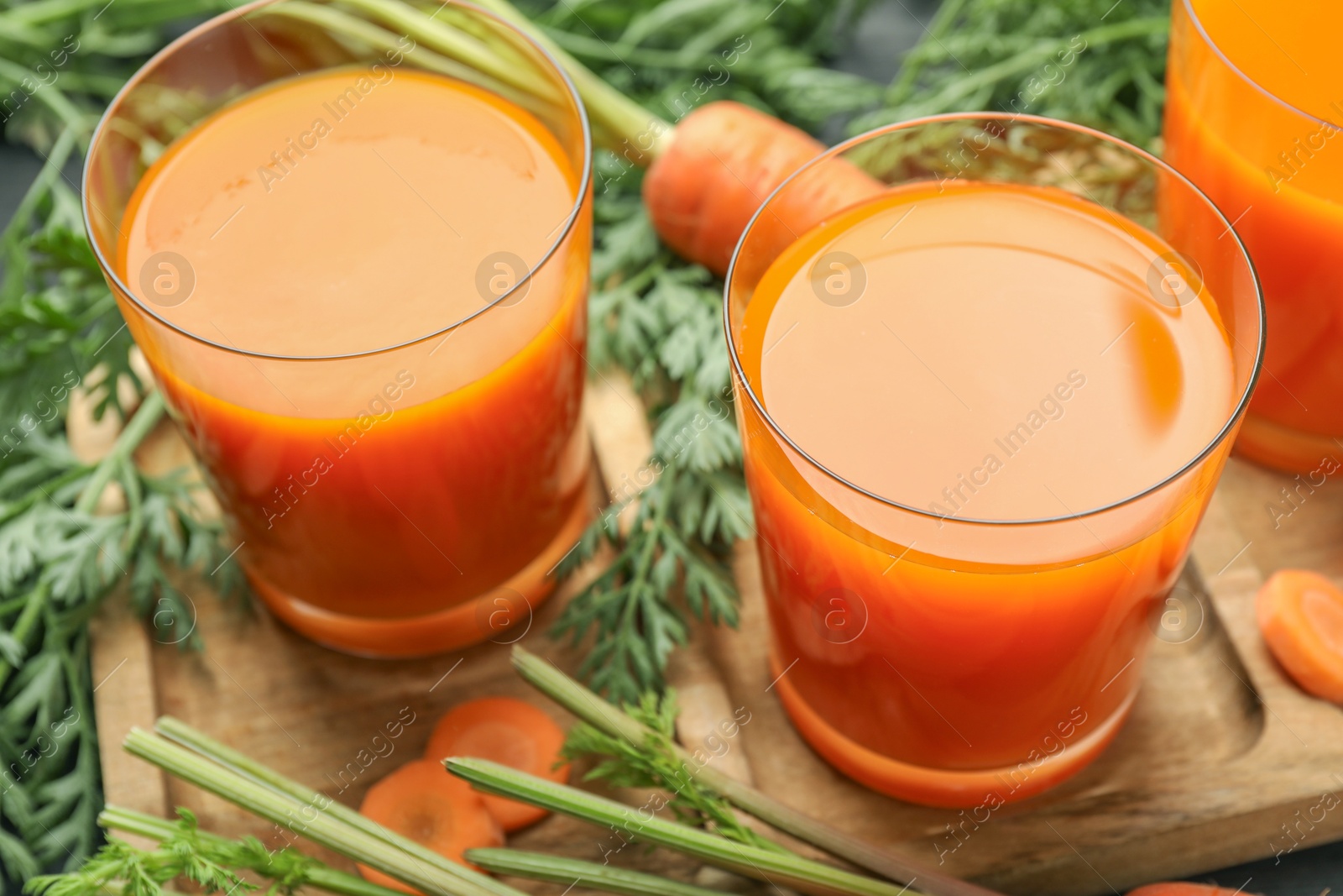 Photo of Healthy carrot juice in glasses and fresh vegetables on table, closeup