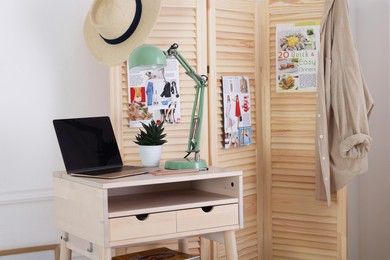 Folding screen, table, laptop and lamp indoors. Interior design