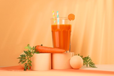 Fresh carrot juice in glass and vegetable on coral background