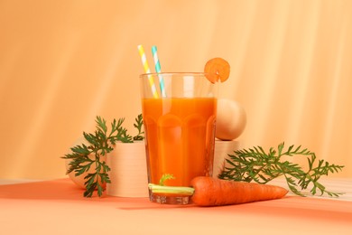 Photo of Fresh carrot juice in glass and vegetable on coral background