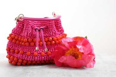 Photo of Stylish pink bag and peony flower on gray table against light background