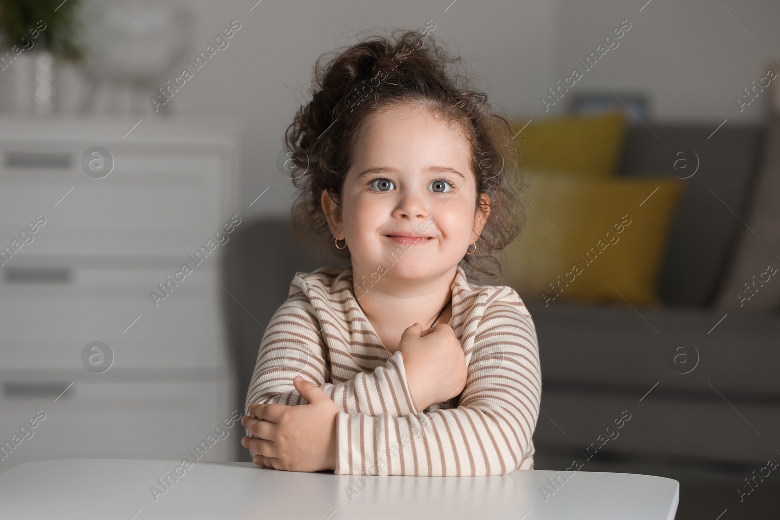 Photo of Portrait of cute girl at table indoors. Adorable child