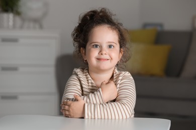 Portrait of cute girl at table indoors. Adorable child