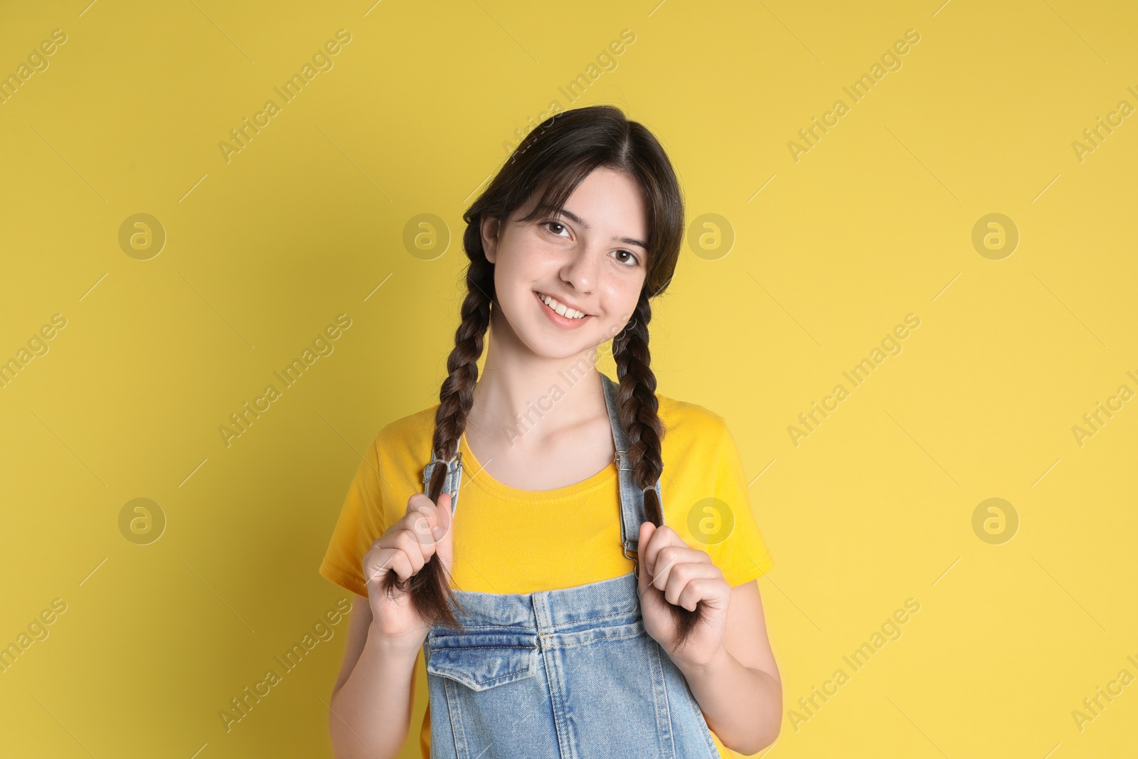 Photo of Portrait of smiling teenage girl on yellow background